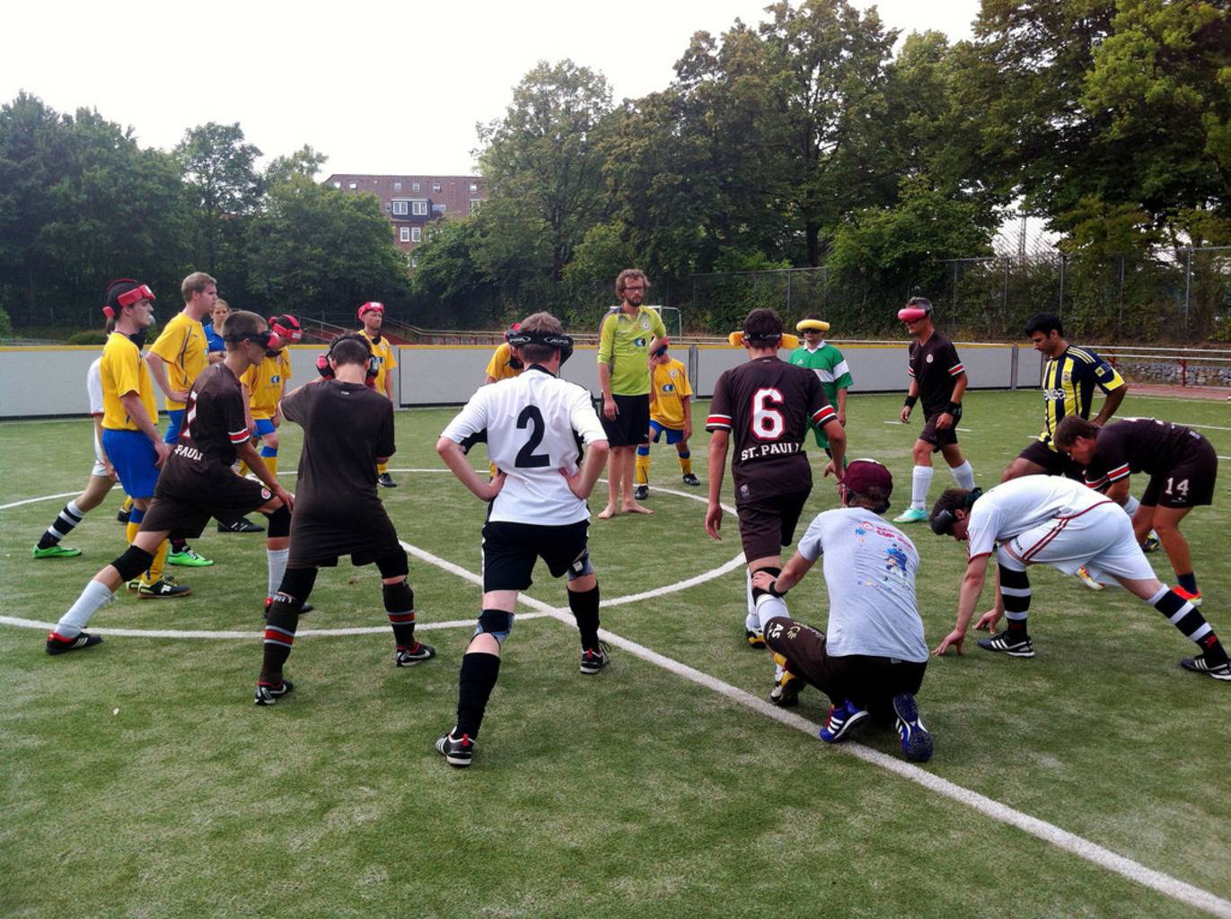 Spieler beider Mannschaften bilden einen großen Kreis auf dem Spielfeld und dehnen sich.